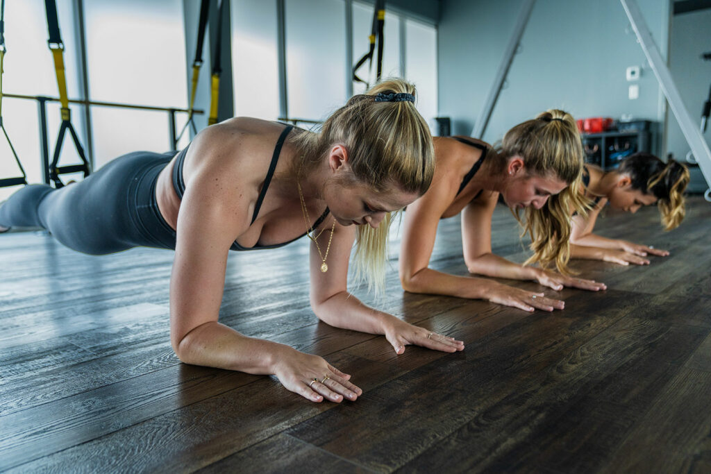 3 women doing planks as part of their overall phsycial fitness program at Pulse Barre and Fitness Studio in Uniontown, OH